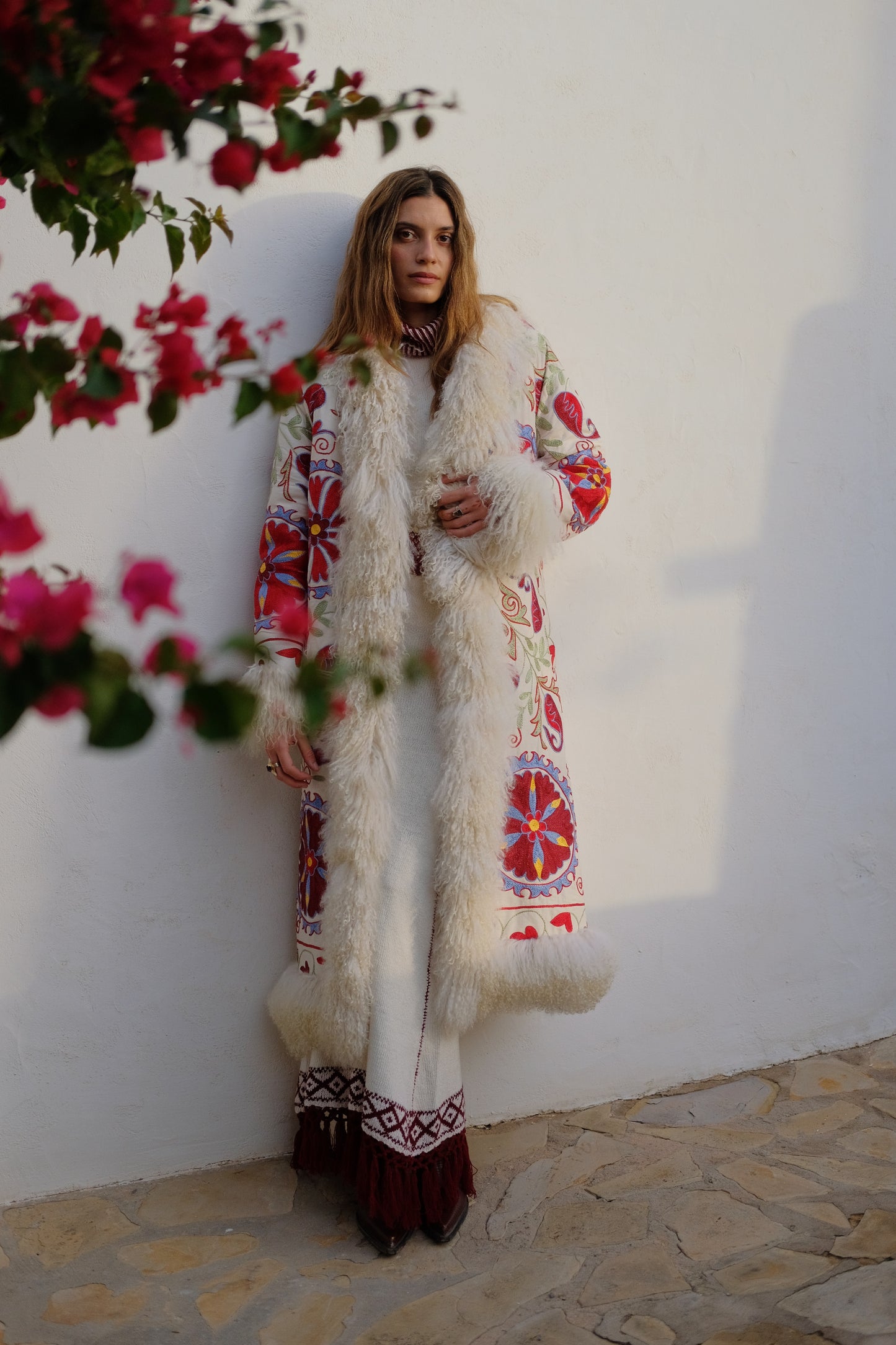 
                  
                    Ivory white knitted two-piece dress set with red and brown woven patterns and tassel hem.
                  
                