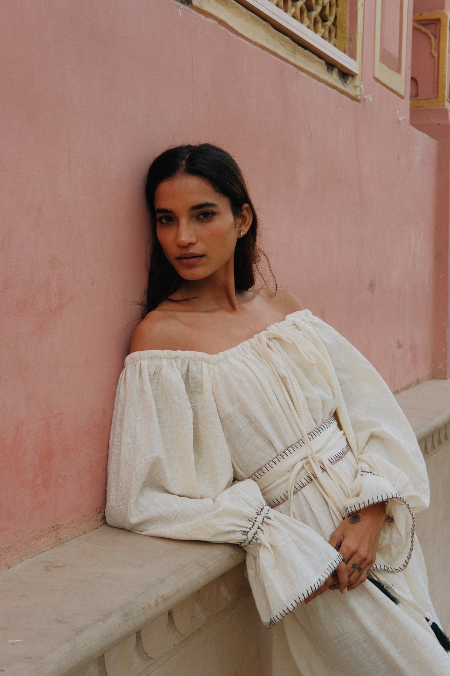 
                  
                    ZAZI Vayana Dress in handwoven Khadi cotton featuring a bohemian maxi silhouette, hand-embroidered details, versatile off-shoulder neckline, long sleeves, and matching belt.
                  
                