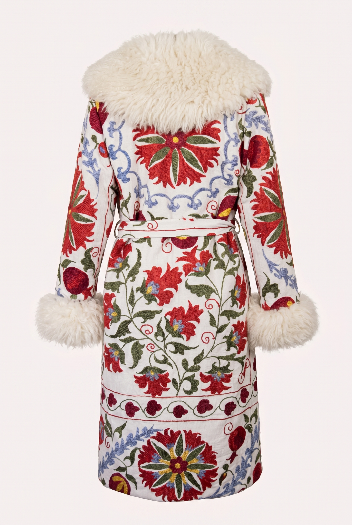 One-of-a-kind ZAZI Afghan coat crafted from vintage velours cotton suzani embroidery with an up-cycled sheepskin lining, featuring a belted 1970s Penny Lane silhouette and handcrafted by women artisans in Afghanistan.
