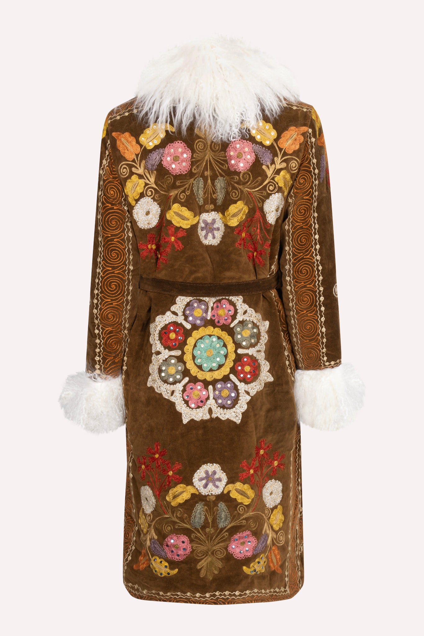 One-of-a-kind ZAZI Afghan coat crafted from vintage velours cotton suzani embroidery with an up-cycled sheepskin lining, featuring a belted 1970s Penny Lane silhouette and handcrafted by women artisans in Afghanistan.