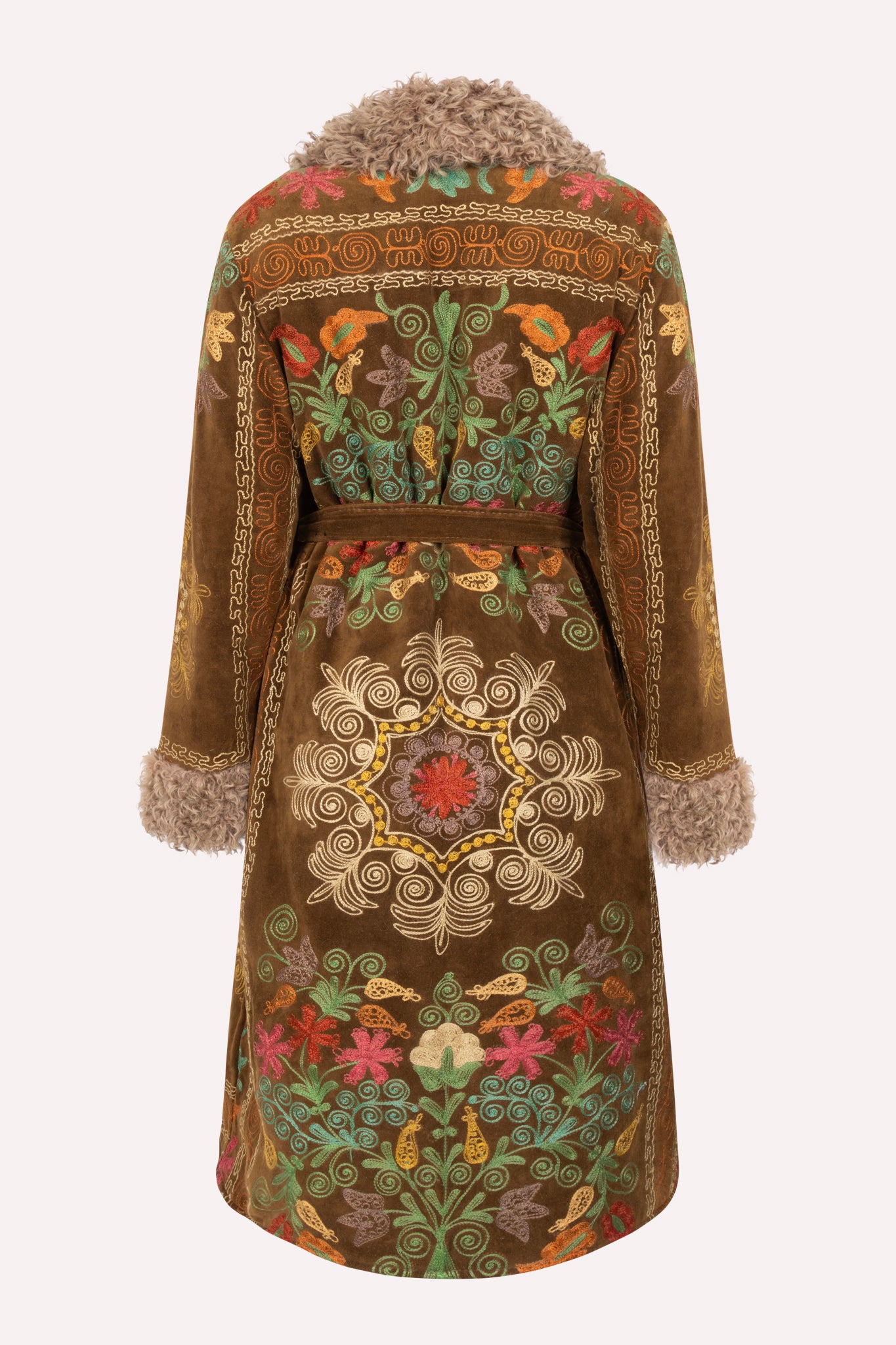 Handcrafted ZAZI Afghan coat made from vintage velours cotton suzani embroidery with upcycled sheepskin lining, featuring a waist-accentuating belt, vintage front buttons, and a 1970s-inspired silhouette, created by women artisans in Afghanistan.
