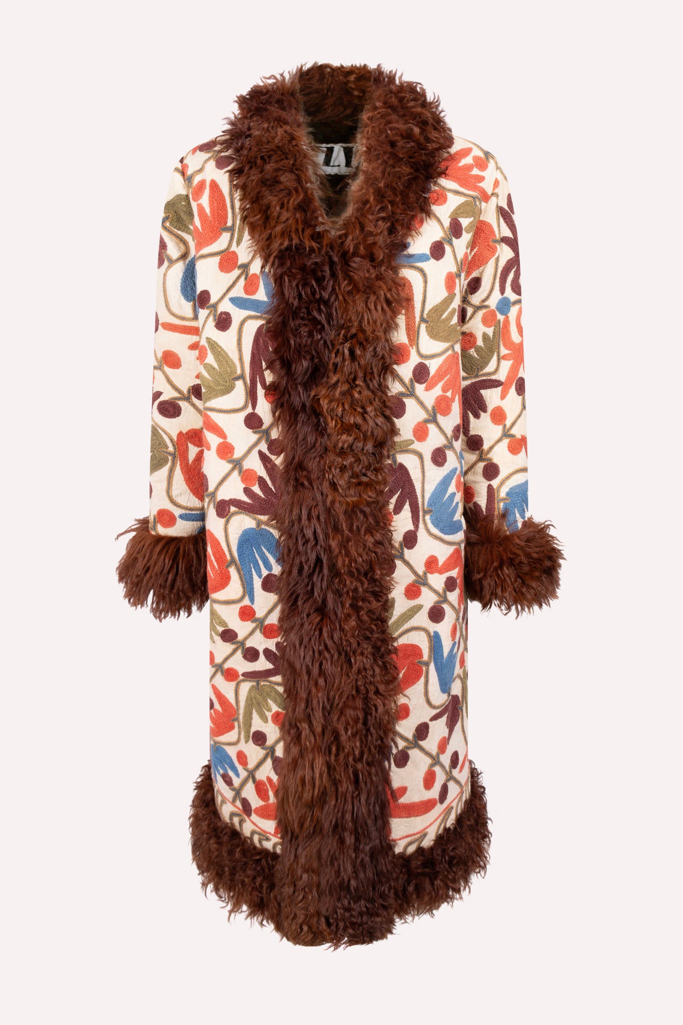 Handcrafted ZAZI Afghan coat made from vintage cotton suzani embroidery with upcycled sheepskin lining, featuring a straight 1970s-inspired silhouette with hook closures, created by women artisans in Afghanistan.