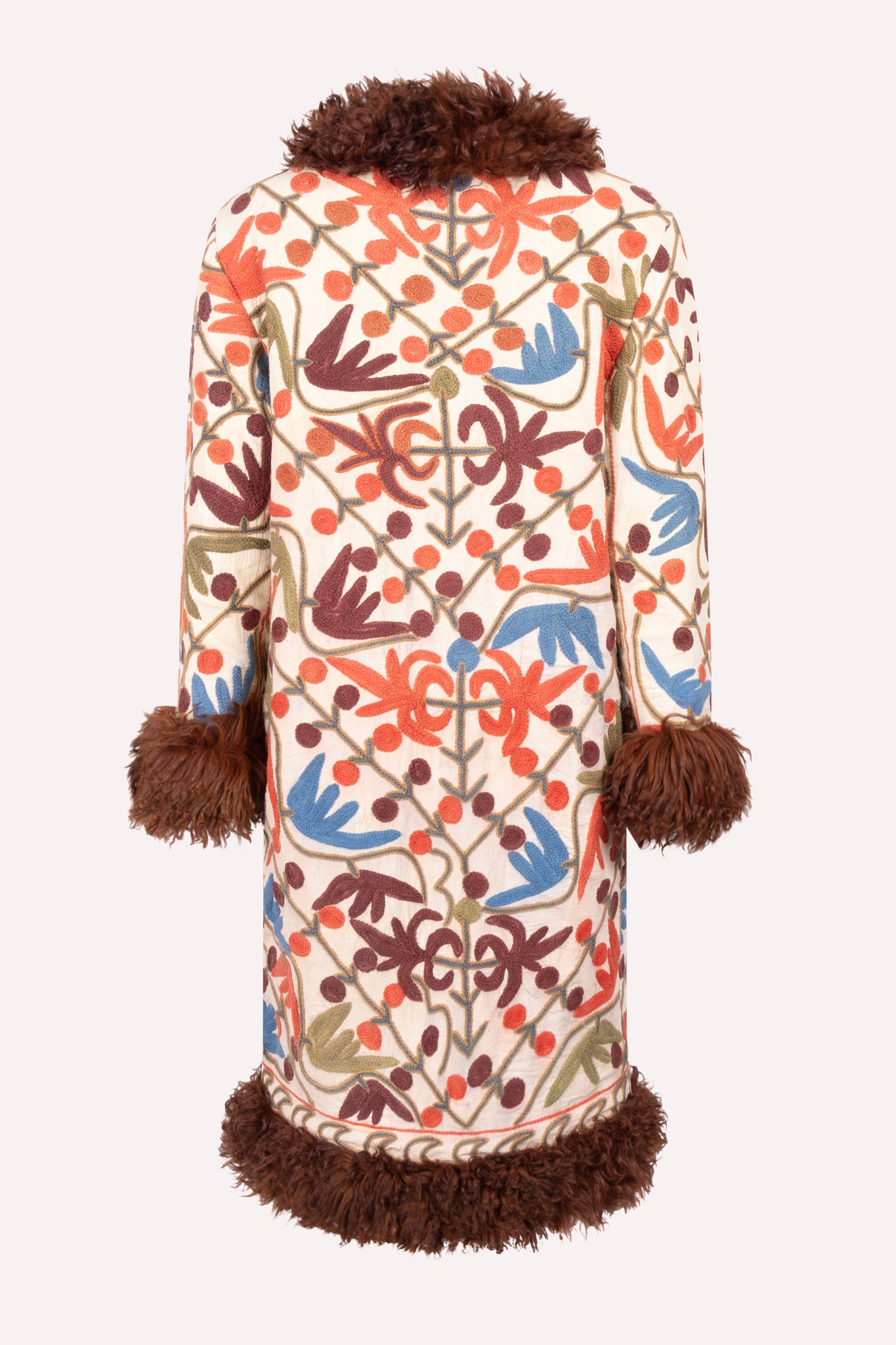 Handcrafted ZAZI Afghan coat made from vintage cotton suzani embroidery with upcycled sheepskin lining, featuring a straight 1970s-inspired silhouette with hook closures, created by women artisans in Afghanistan.