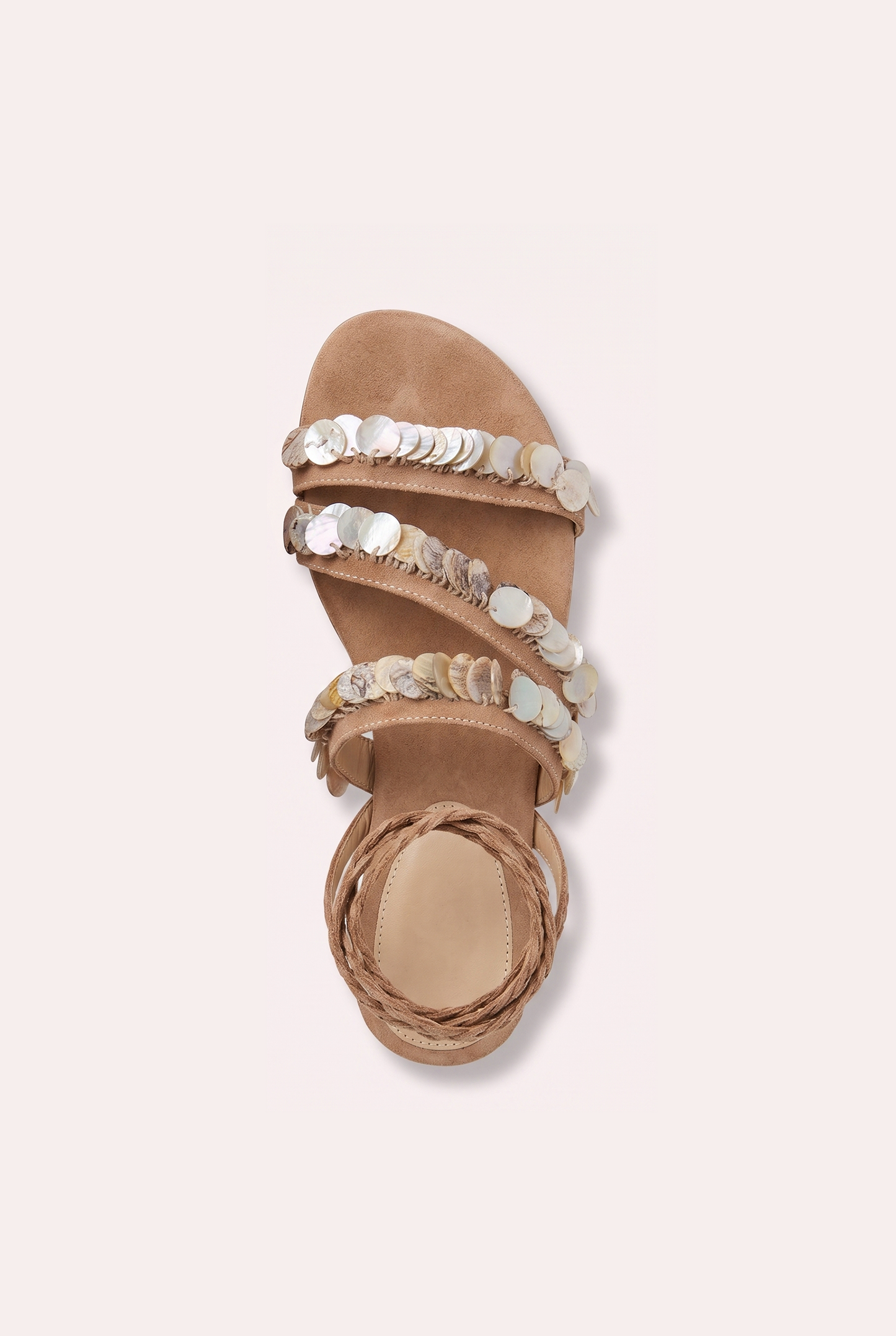 
                  
                    Handcrafted tan suede flat sandals with mother of pearl beads and braided wrap-around ankle ties.
                  
                